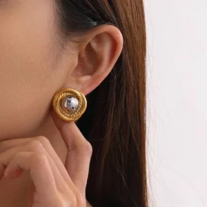 Two-tone twisted gold and silver stud earrings close-up worn on ear side view modern aesthetic