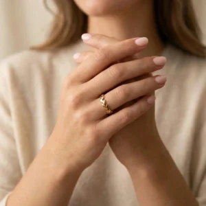 Stackable 18K gold rings on woman's hands close-up showing minimalist twisted band styles and delicate design details
