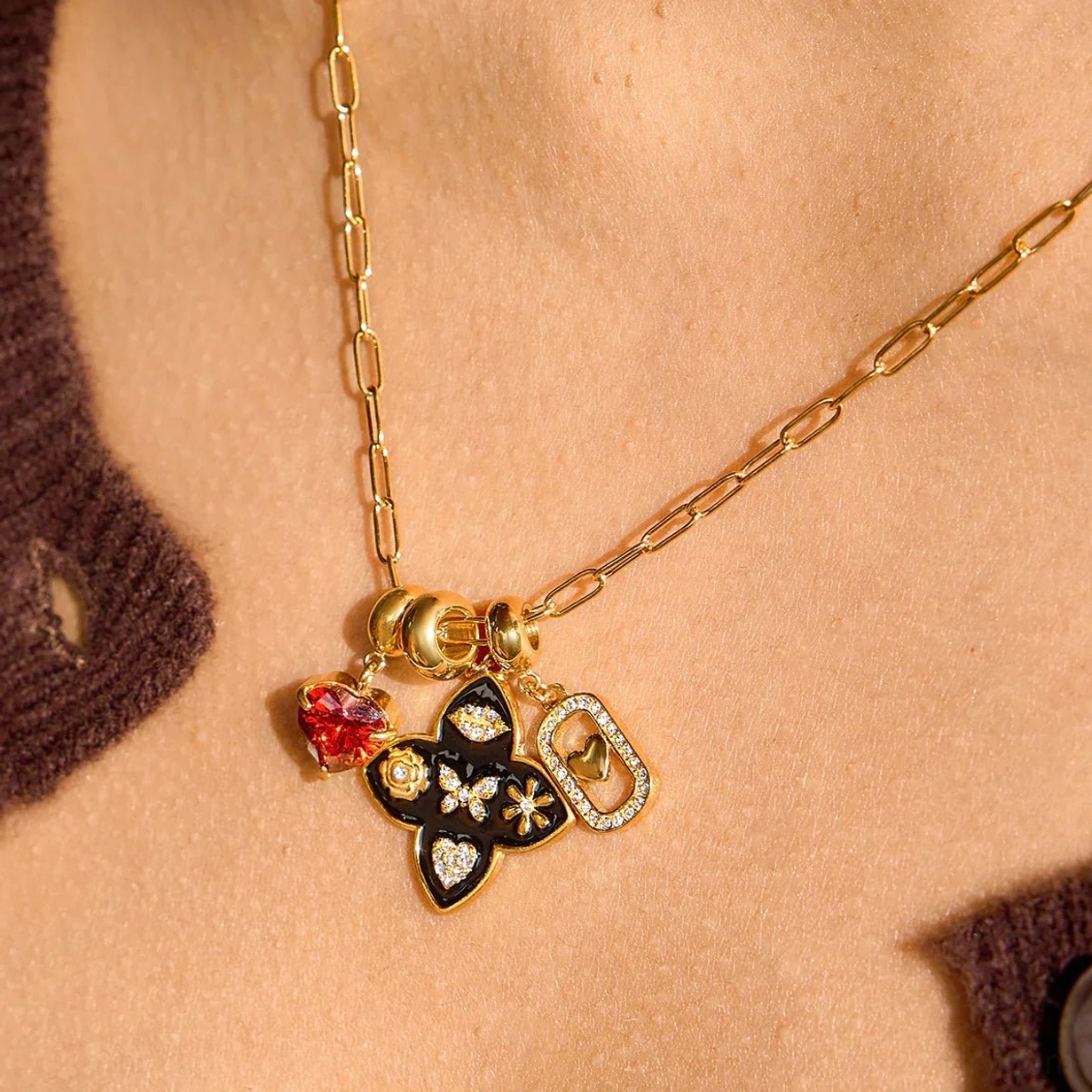 18k gold vintage charm necklace worn on neck close-up view on female model with brown knitwear