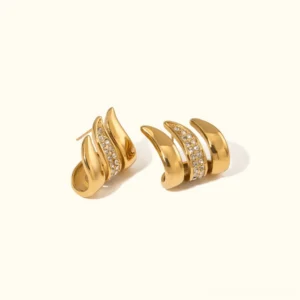 18K gold wave stud earrings with crystal pavé detail front flat lay on white background showing polished gold finish