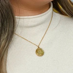 18K gold ocean wave pendant necklace worn on neck close-up shot model wearing white turtleneck sweater collarbone styling