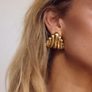 Close-up side view of 18K gold wave earrings worn on female model ear showing wavy silhouette and polish finish