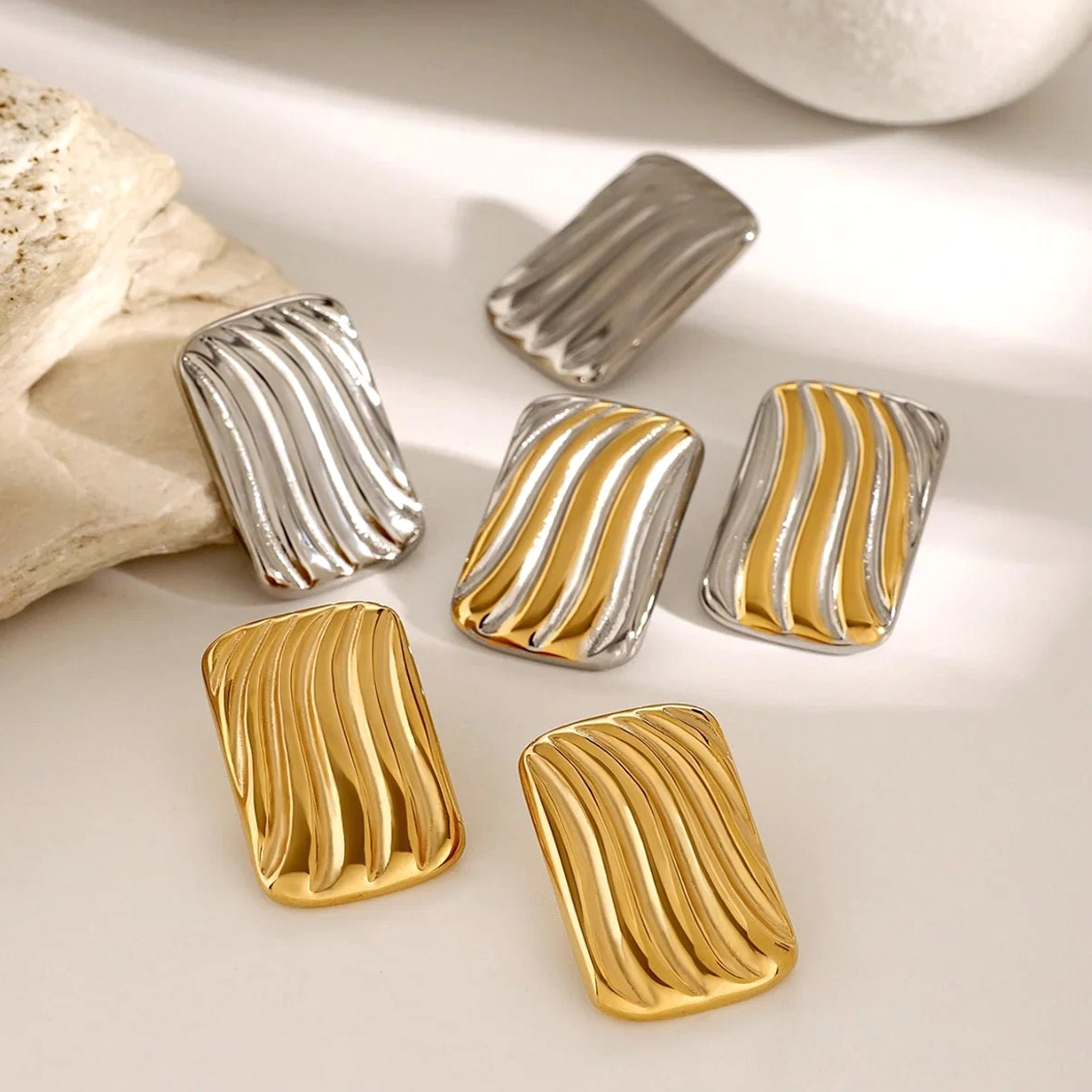 18K gold stud earrings all color variants two-tone silver yellow gold stone background