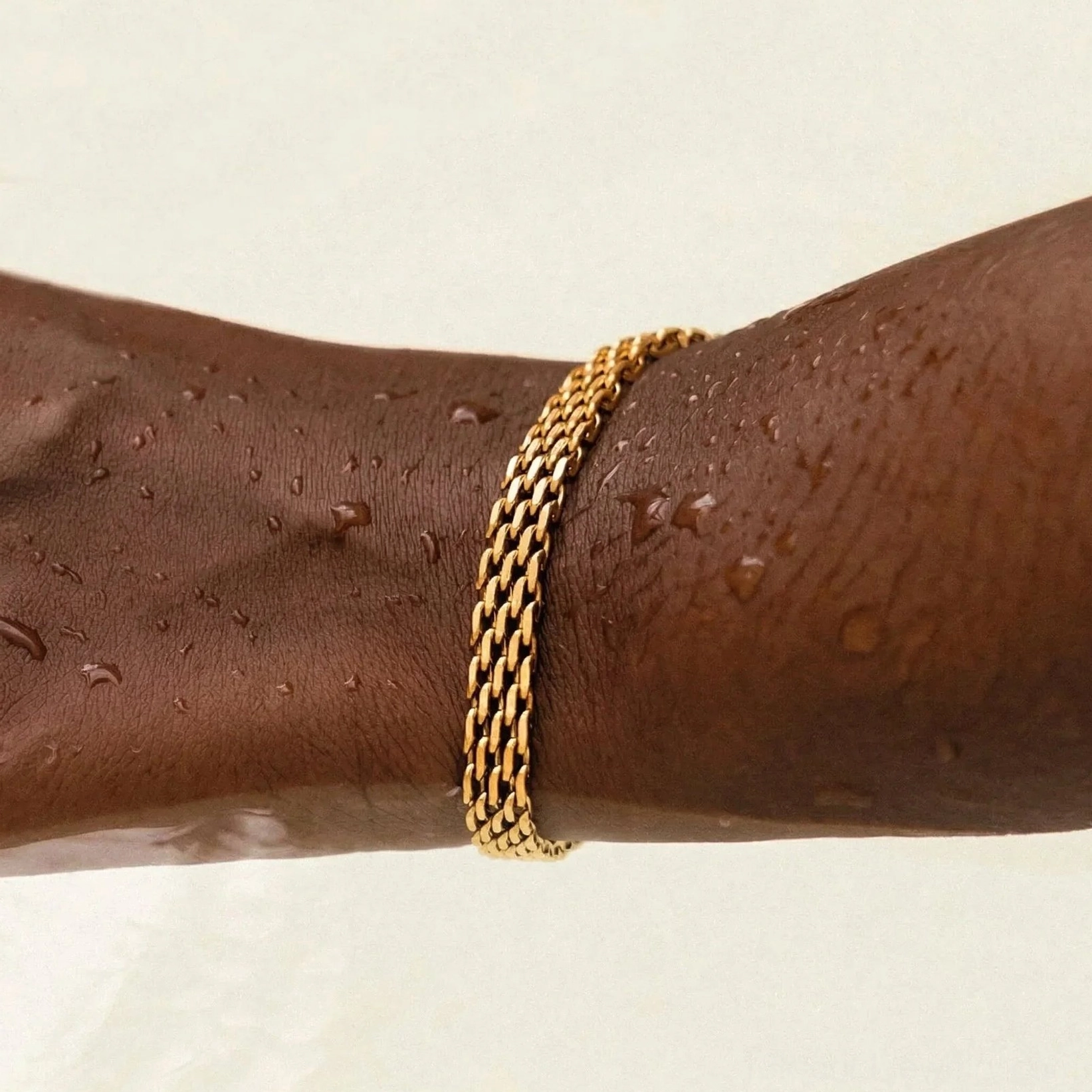 18K Gold Woven Chain Bracelet on Dark Skin Tone Wrist with Water Droplets - Durability Feature