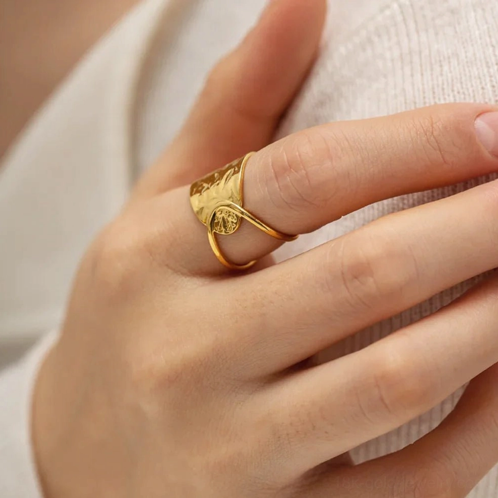 Women's hand wearing 18K gold open wrap ring with hammered texture on index finger