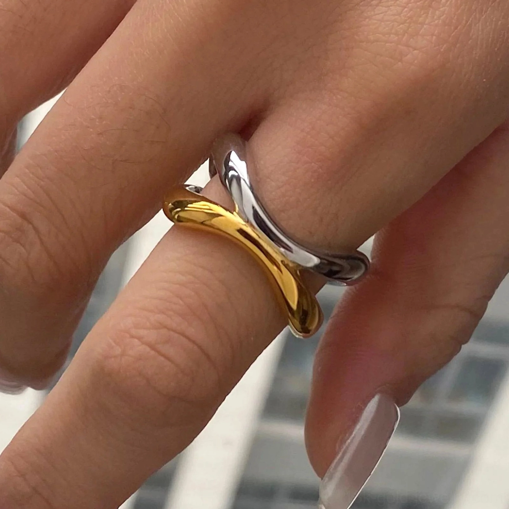 Two-tone gold and silver twisted ring worn on female hand, showing natural fit and elegant styling
