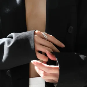 Silver twisted ring worn on female model's hand with black blazer, showcasing minimalist metallic design and everyday wearability