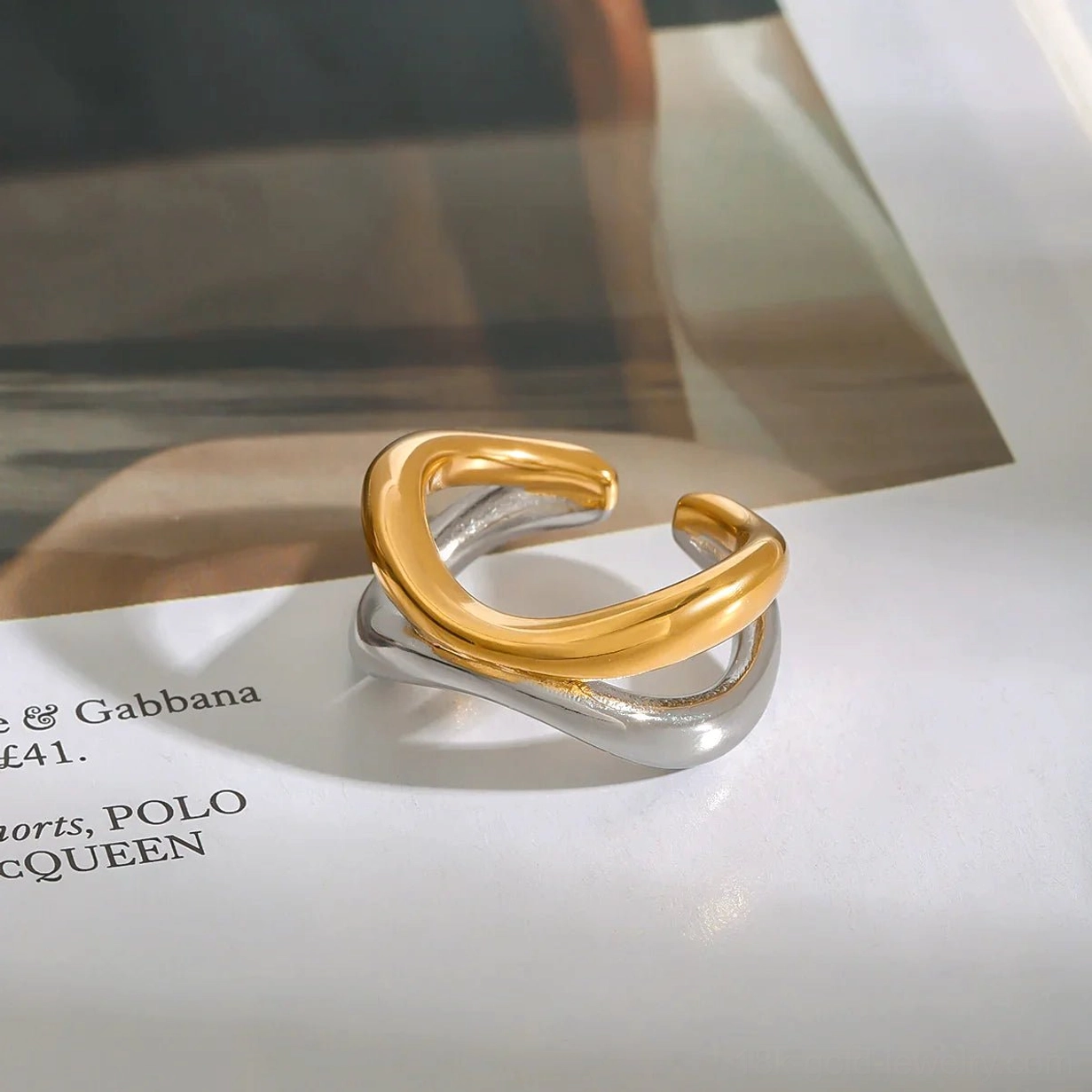 18K gold two-tone twisted open ring placed on magazine, glossy metal finish detail