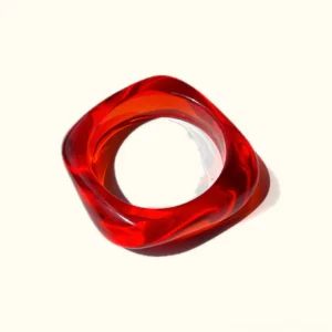 Cherry Pop bright red acrylic bangle bracelet with twisted rounded square shape, flat lay top-down view on white background