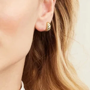 Gold croissant huggie earrings worn on ear, side profile showing snug fit and polished finish