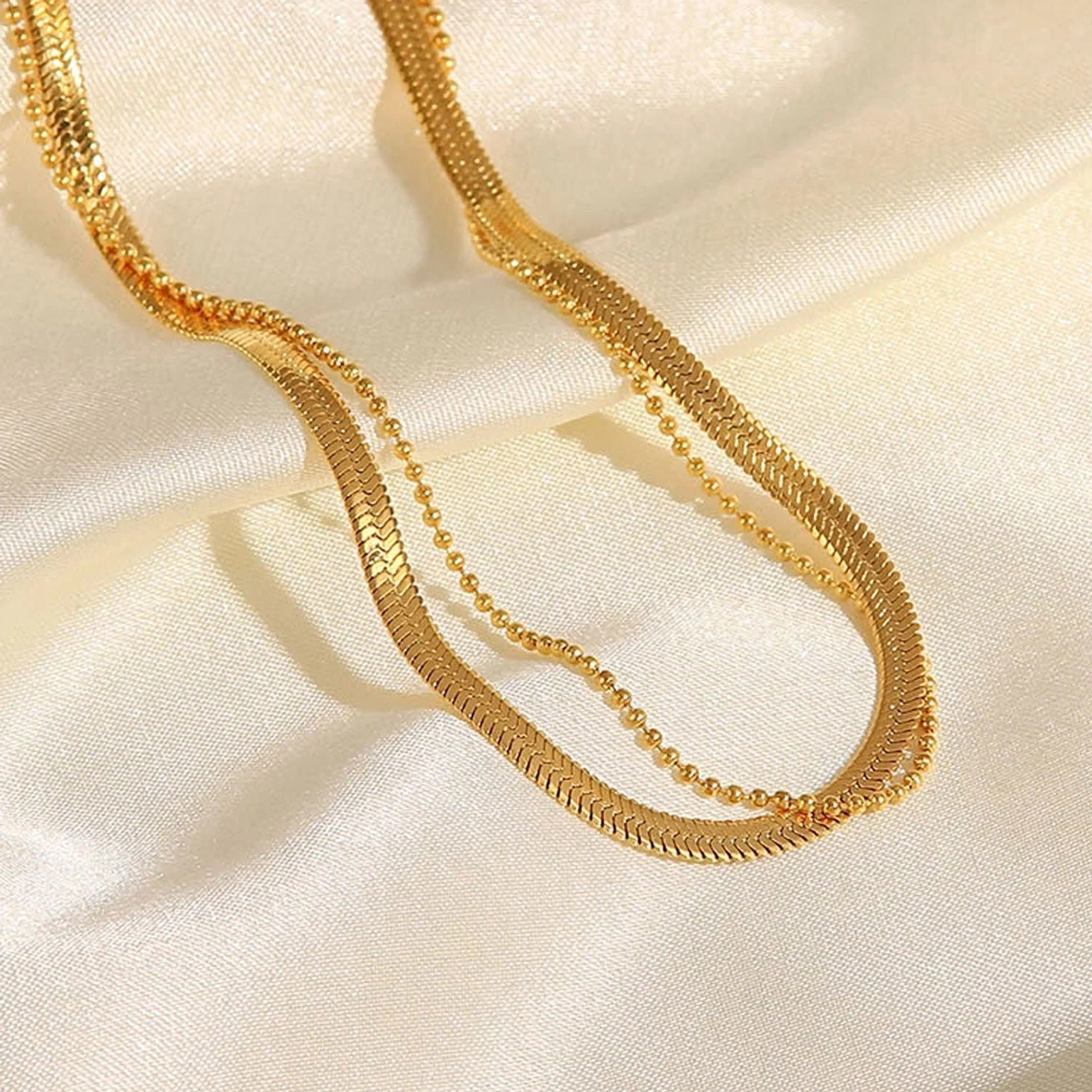 Double layered gold anklet close-up on satin silk - glossy 18K gold chain details