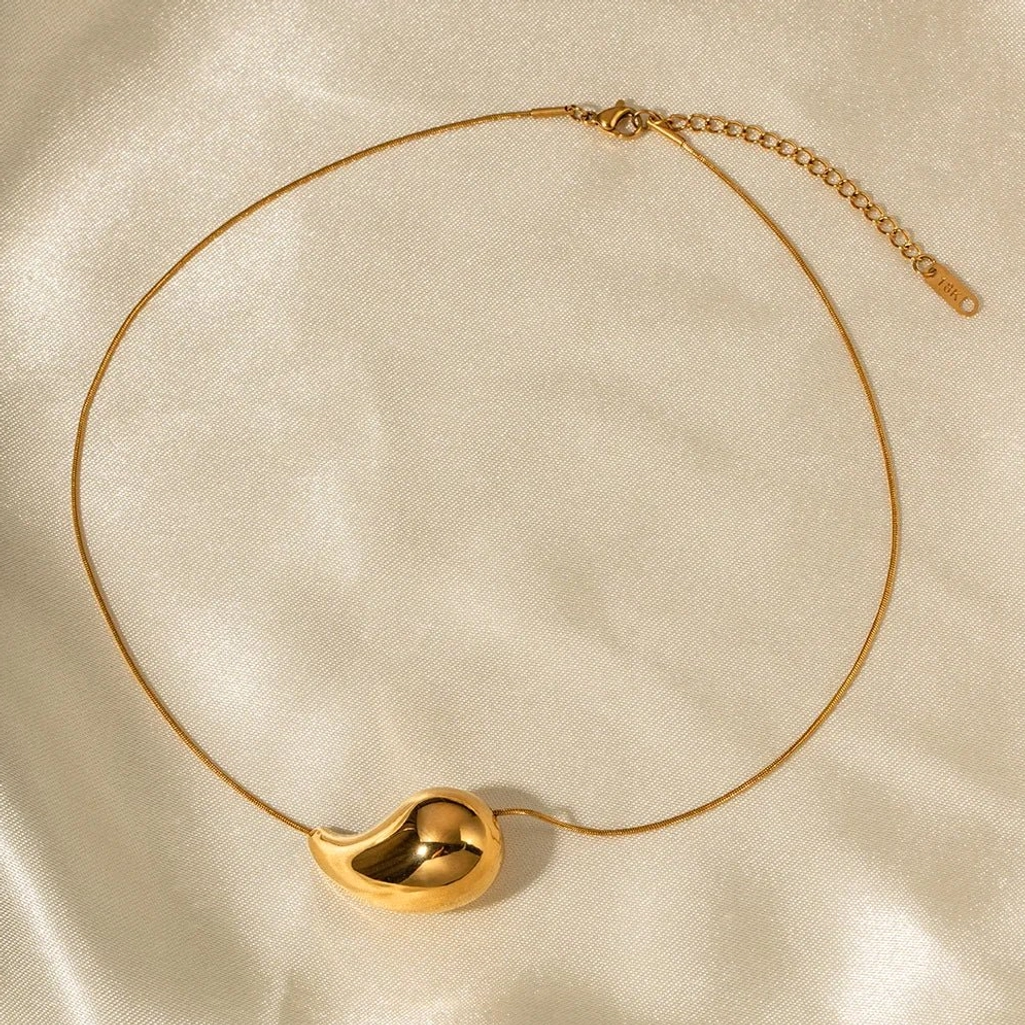 Gold teardrop choker necklace with adjustable extender - overhead silk fabric display showing clasp and extension chain