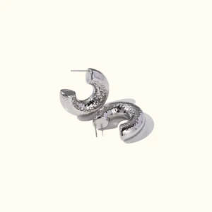 Hammered stainless steel hoop earrings flat lay on plain background showcasing textured C-shaped design and polished metallic finish