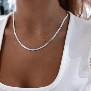 Minimalist herringbone silver chain choker necklace close-up on model wearing white top, demonstrating smooth flat chain design