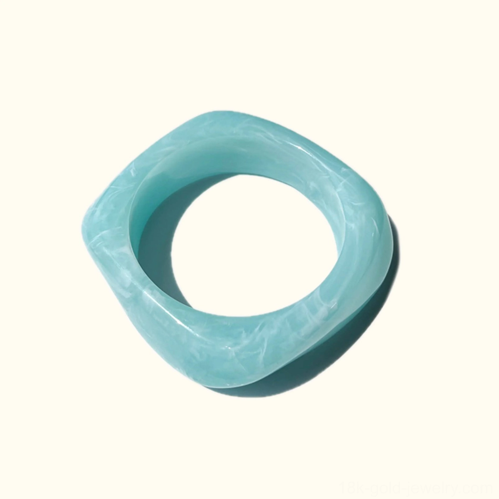 Ocean Mist light cyan acrylic bangle bracelet with white marbling pattern, twisted rounded square silhouette in top-down flat lay