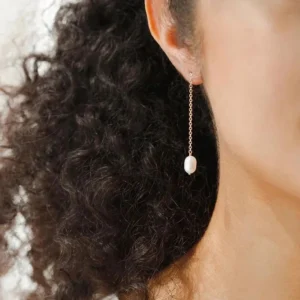 Pearl tassel threader earrings close-up side view worn on woman showing teardrop pearl pendant dangling from gold chain