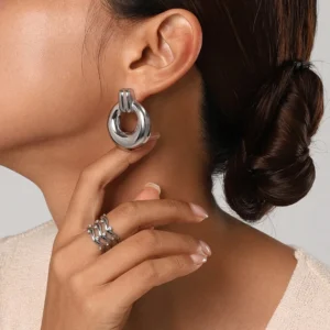 Silver hoop earrings worn on ear, close-up side profile showing shiny metal material and comfortable fit on earlobe