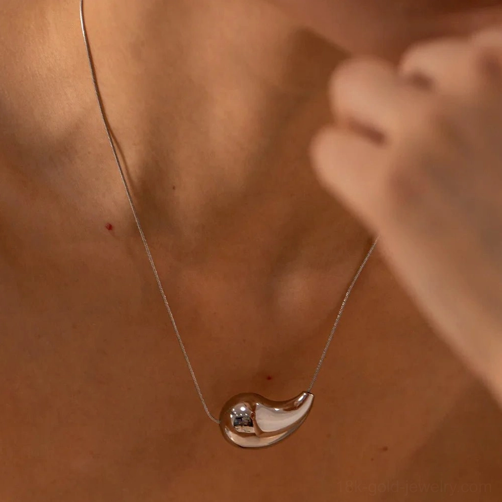 Silver teardrop pendant necklace on model neck - close-up detail shot showing sleek finish and minimal chain design
