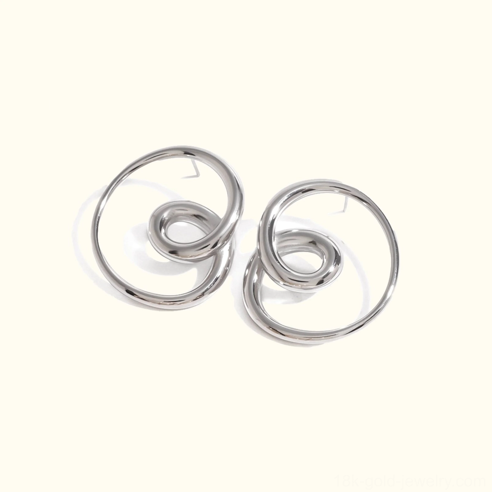 Silver twisted spiral stud earrings flat lay front view polished studio background