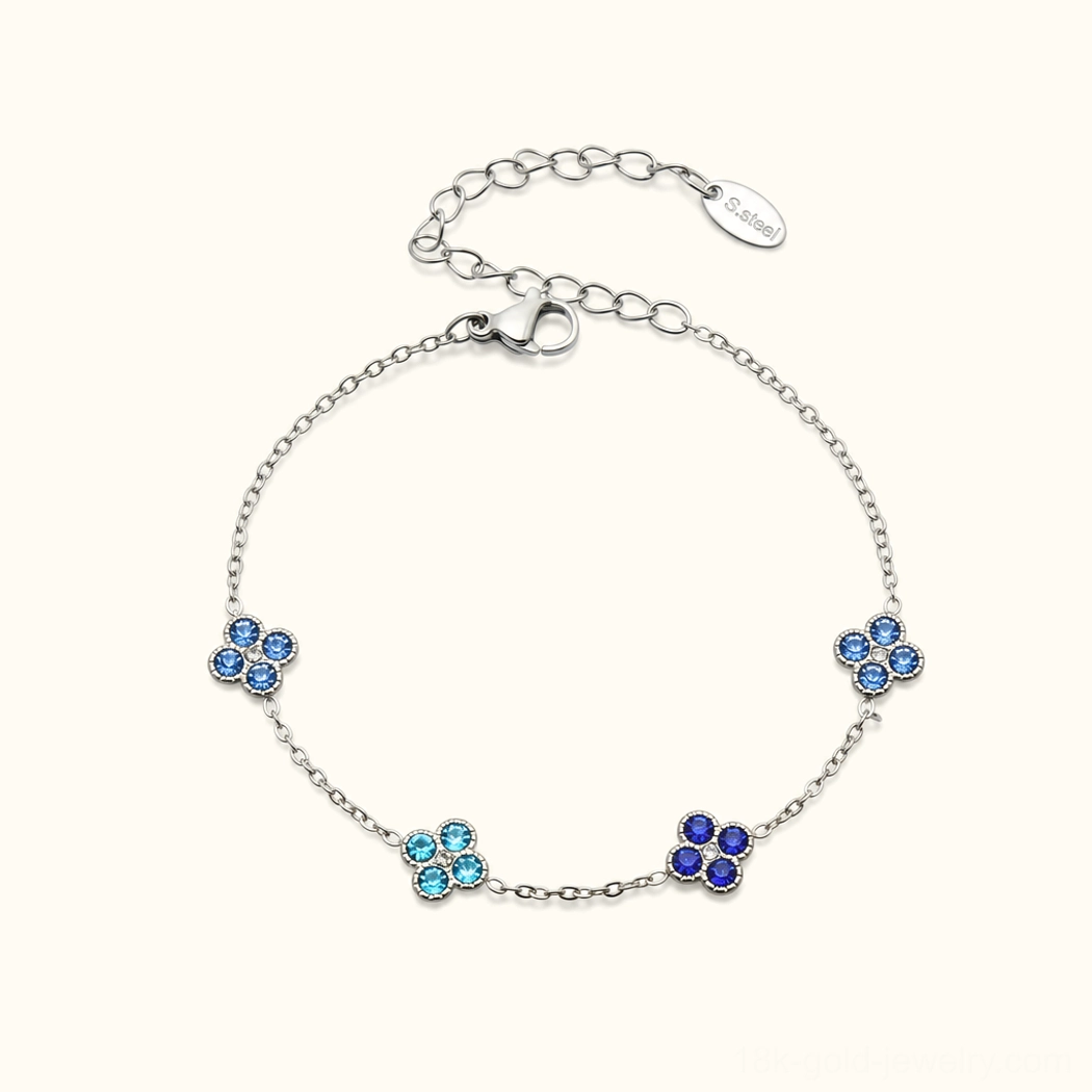 Sterling silver four-leaf clover bracelet with blue sapphire gemstone charms, fine jewelry flat lay