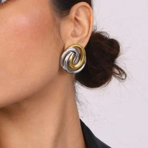 Two-tone gold and silver spiral earrings worn on model ear - side profile close-up of geometric twisted design